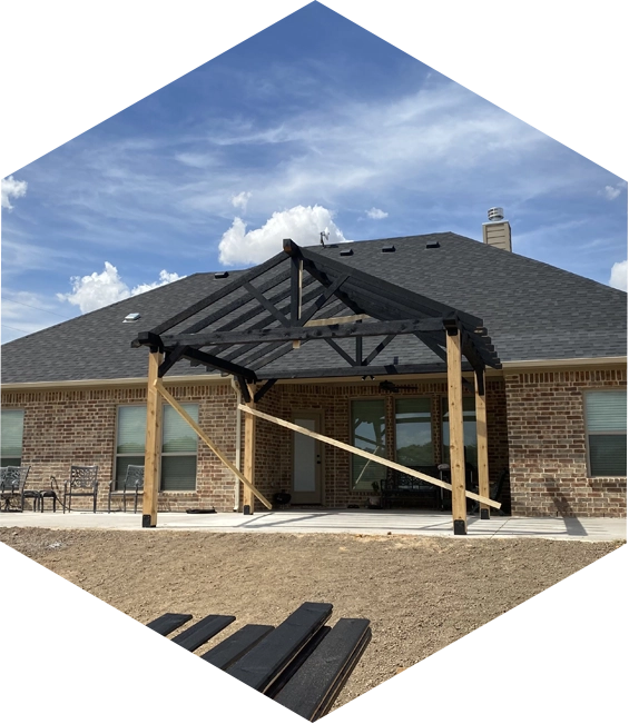 Black pergola under construction on a brick house.