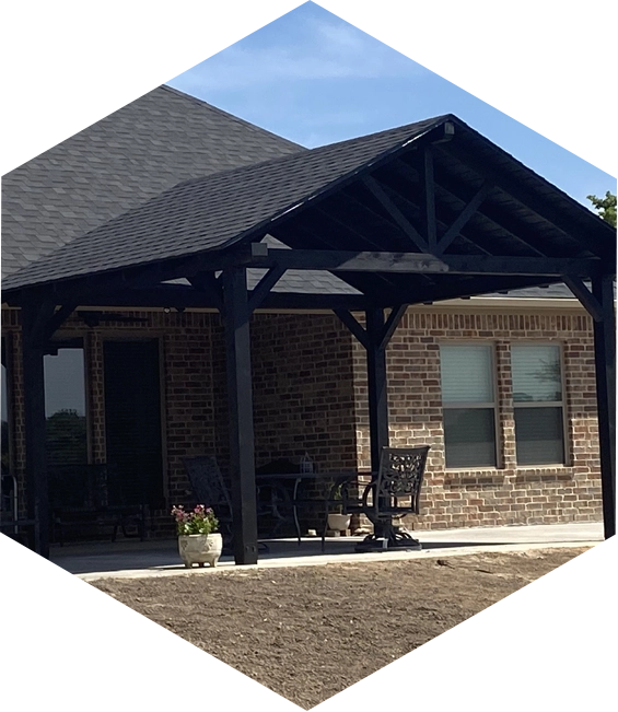 Black pergola with a brick house and patio furniture.