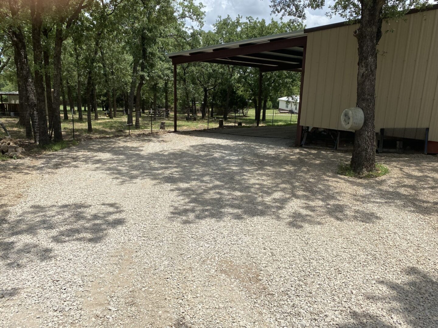 A gravel area with trees and a shed.