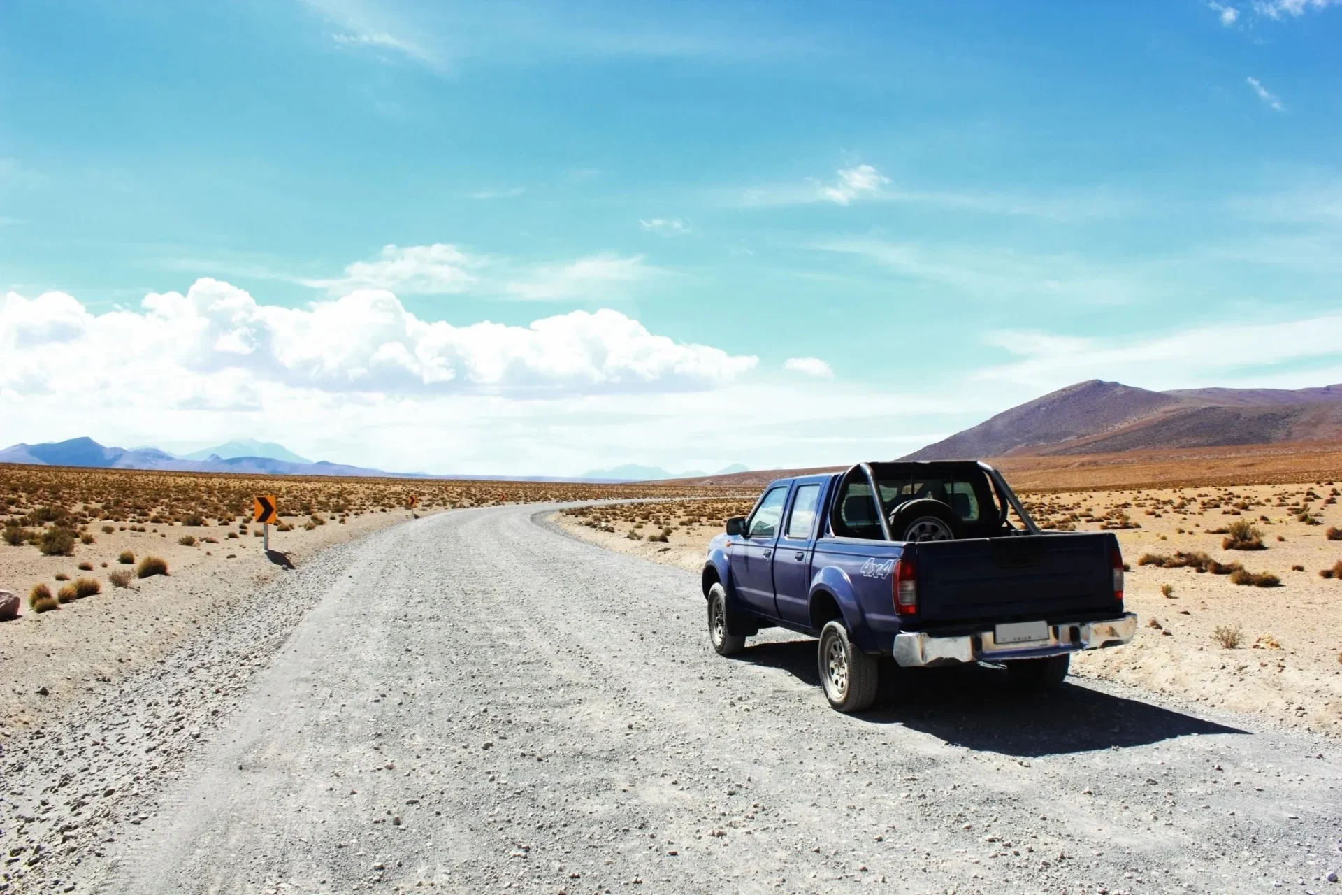 A truck is parked on the side of a dirt road.